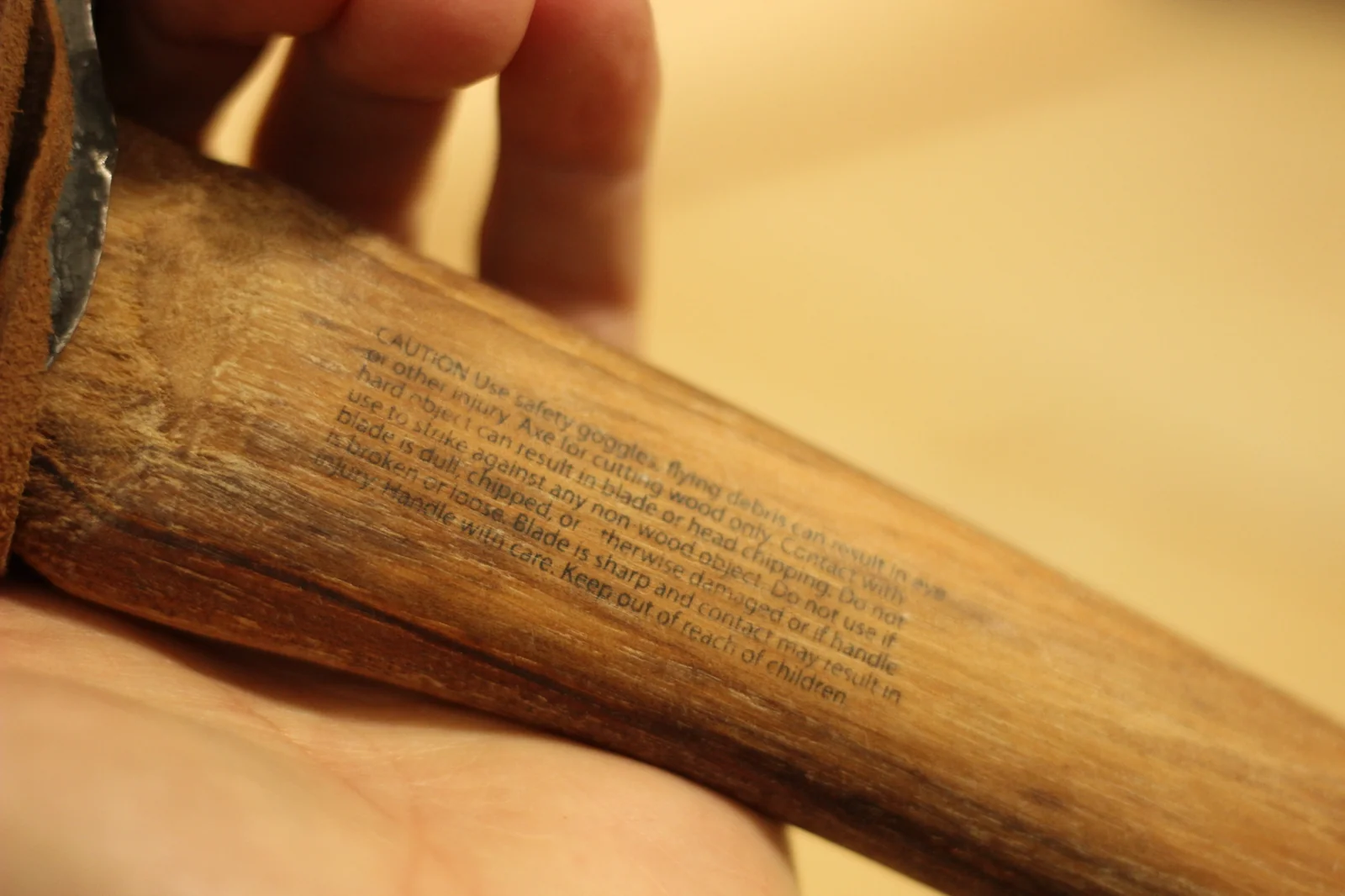 Macro shot of the caution warning text laser-engraved into the hickory handle reading CAUTION Use safety goggles flying debris can result in eye or other injury and continuing warnings