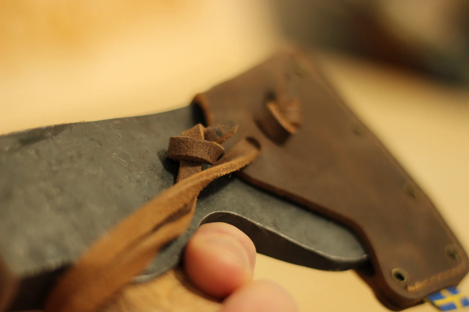 Close-up of the leather sheath strap looping over the axe head with the brass stud closure