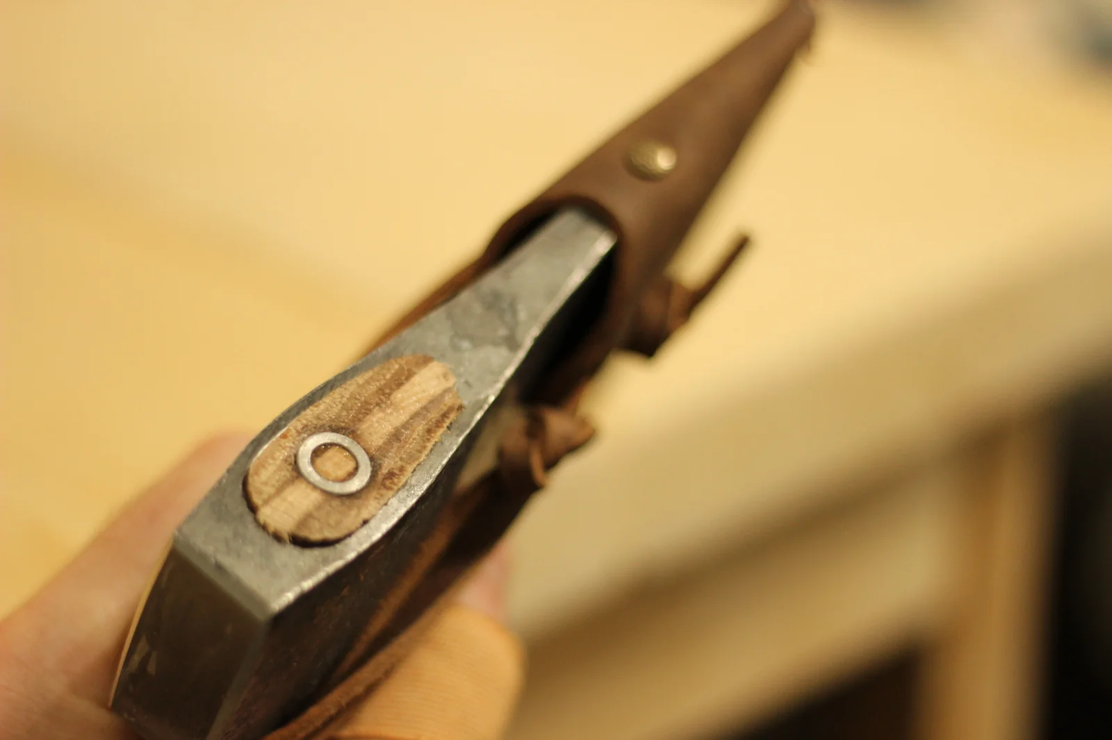 View of the leather sheath bottom edge with brass rivets and the small Swedish flag tag visible at the bottom corner