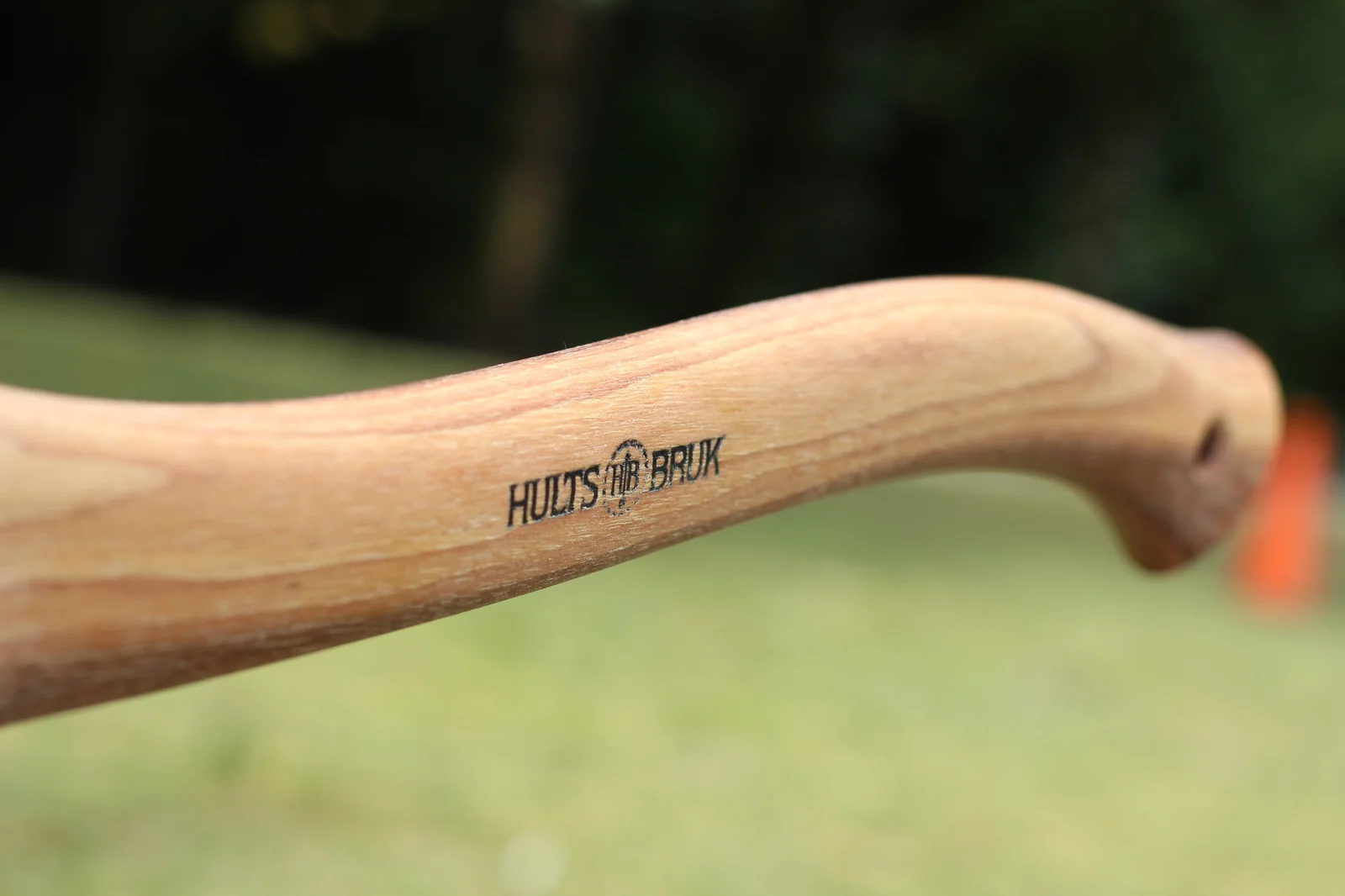 Macro of the Hults Bruk laser-printed brand mark on the curved hickory handle photographed outdoors with green grass in the background