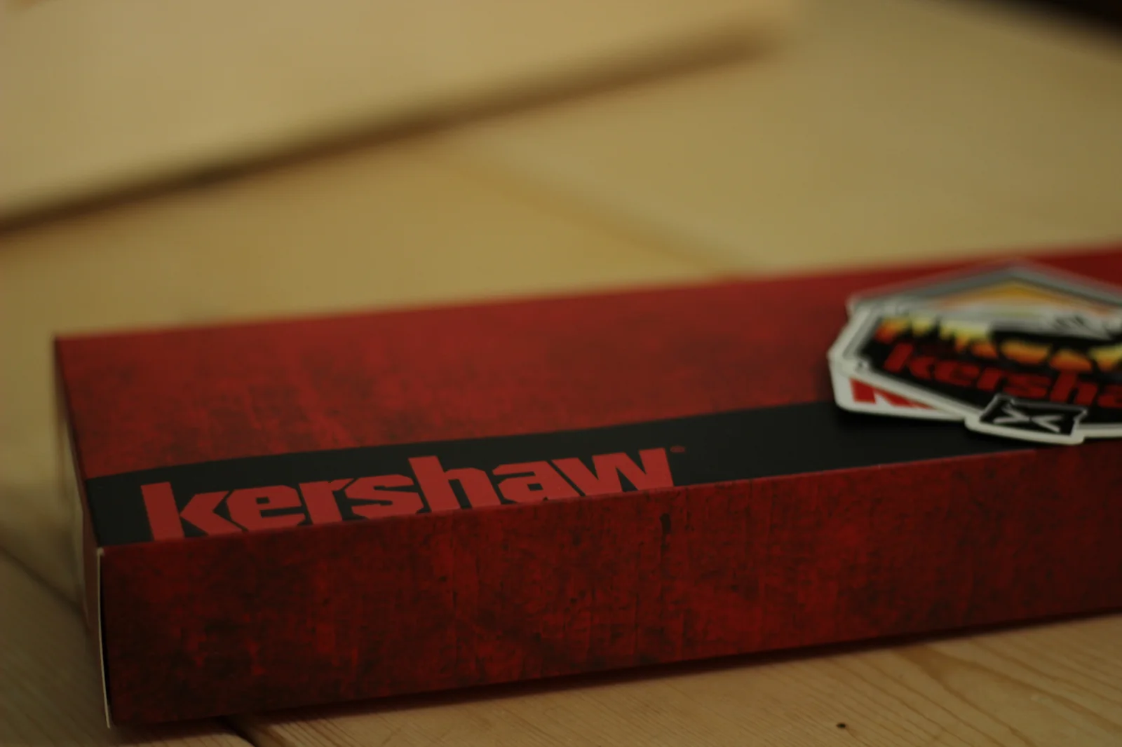 Red Kershaw retail box with the kershaw logo in a black band and a Kershaw deer-silhouette sticker resting on top