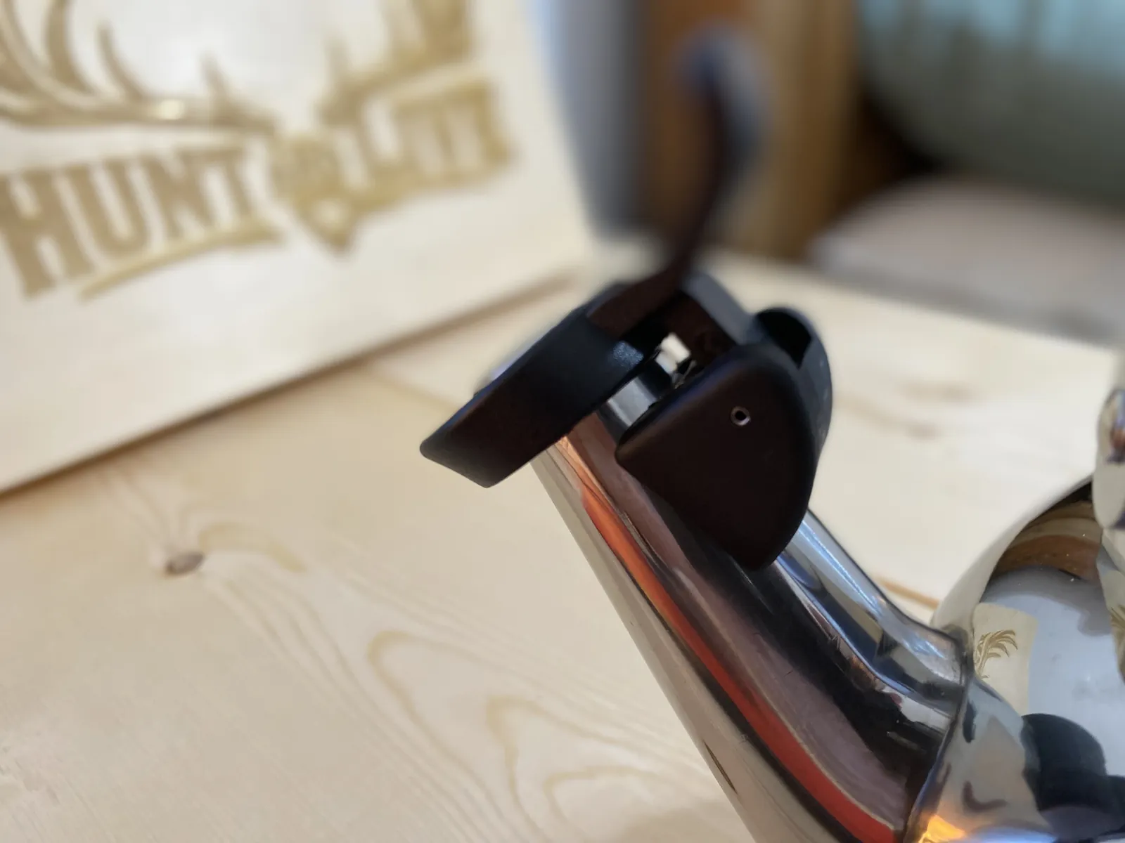 Close-up of the spring-loaded thumb lever and hinged whistle cover at the spout