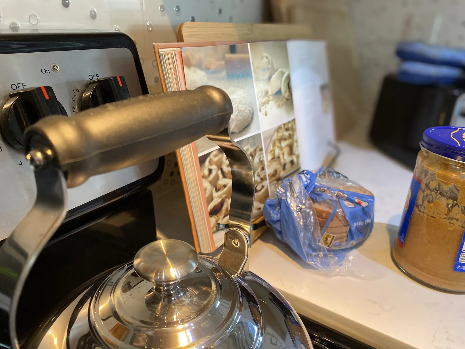 Kettle on the stovetop with handle upright, beside an open cookbook