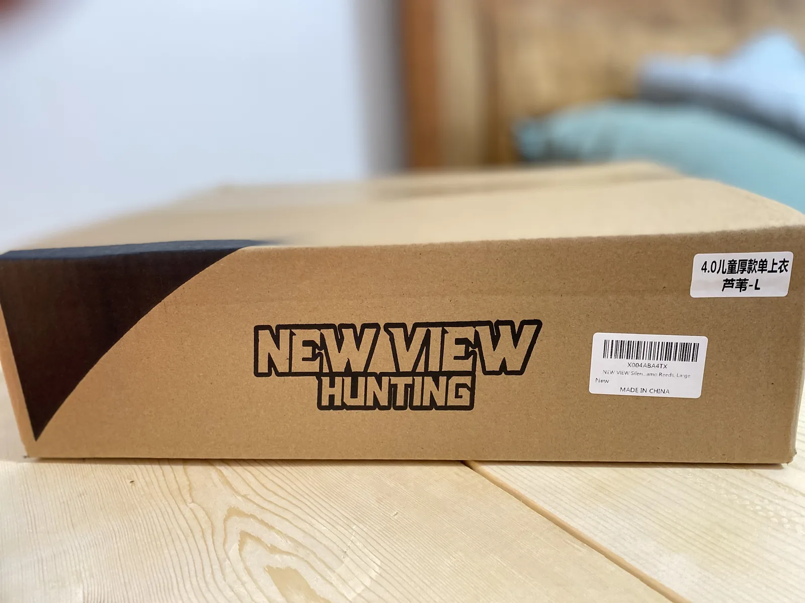 A plain corrugated carton on a pale wood table with the NEW VIEW HUNTING wordmark printed on the side