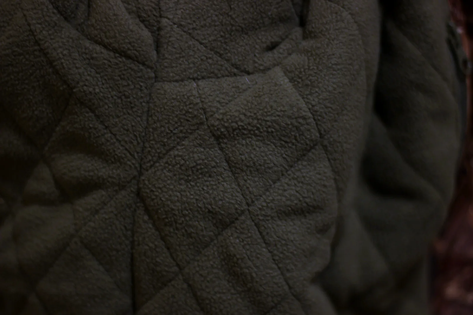 Close-up of the olive quilted padded lining inside the jacket body