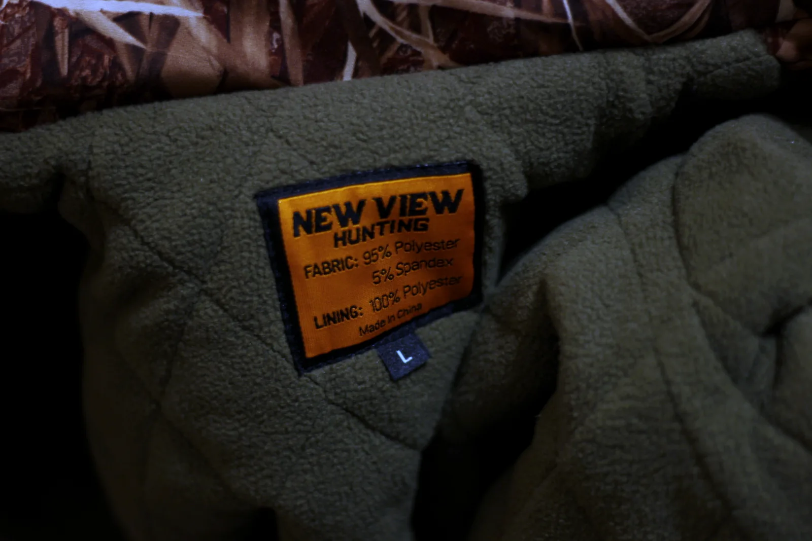 The New View Hunting label stitched into the quilted olive lining with the size L tab