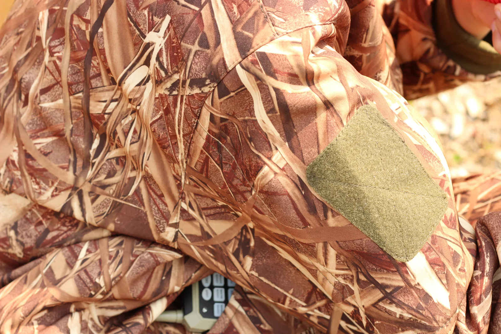 An olive reinforcement panel set into the shoulder of the camo jacket