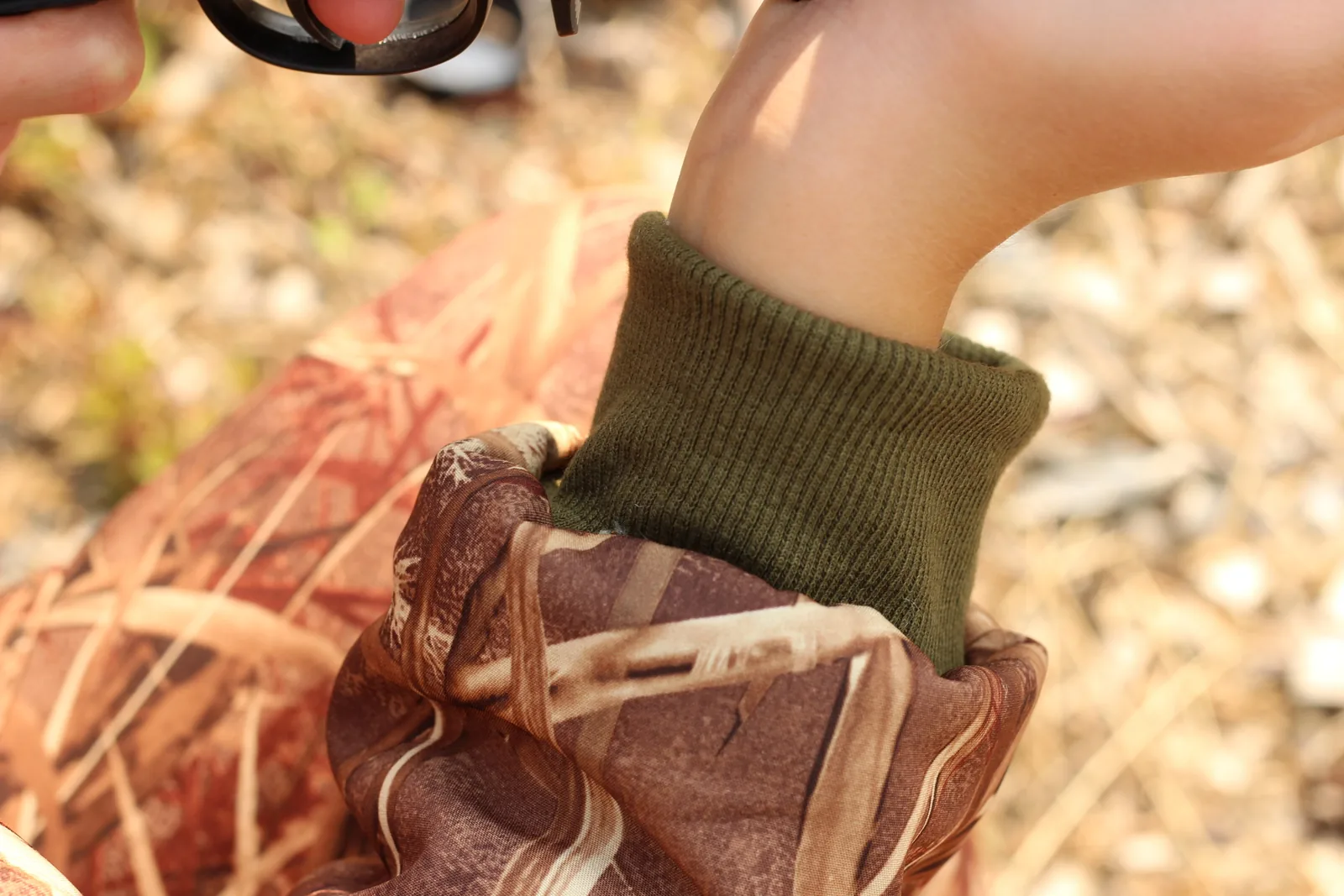 Close view of the ribbed olive knit cuff closed snugly around a child's wrist