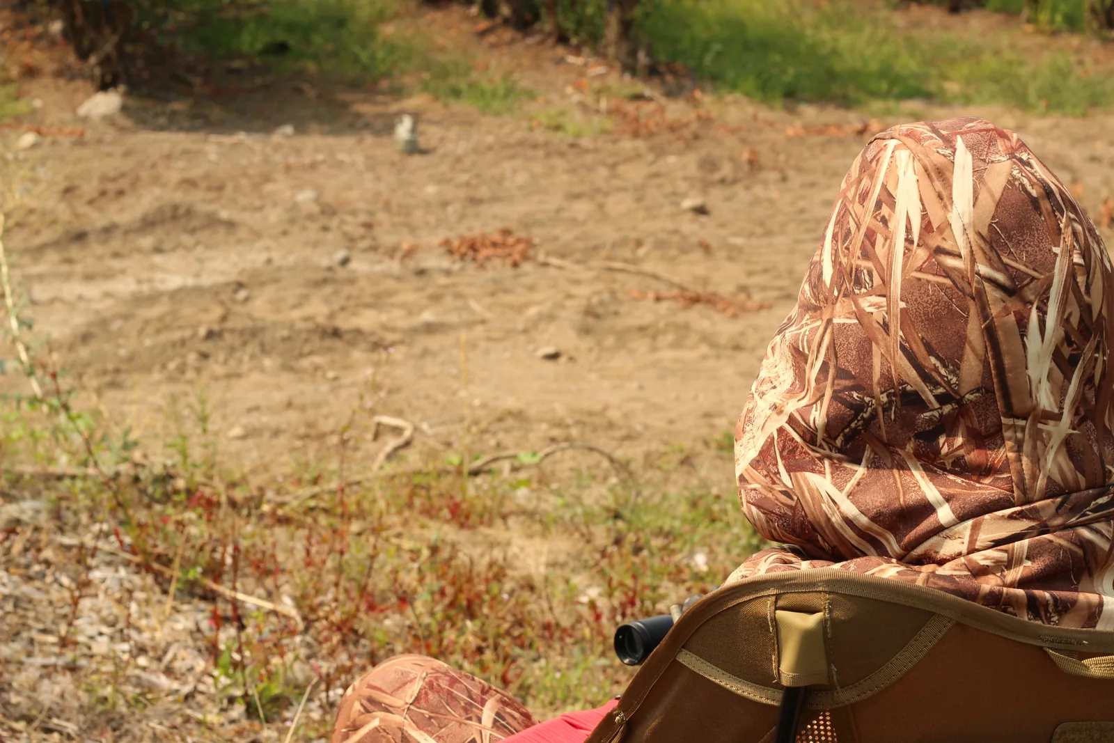The young hunter sitting very low in the camp chair, mostly hidden against the dry ground