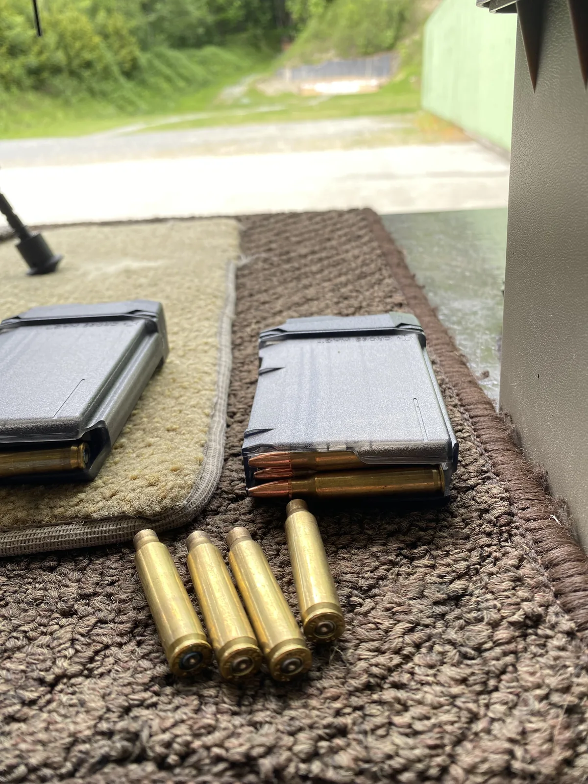Fired .223 brass and two loaded steel AI-pattern magazines on a shooting mat