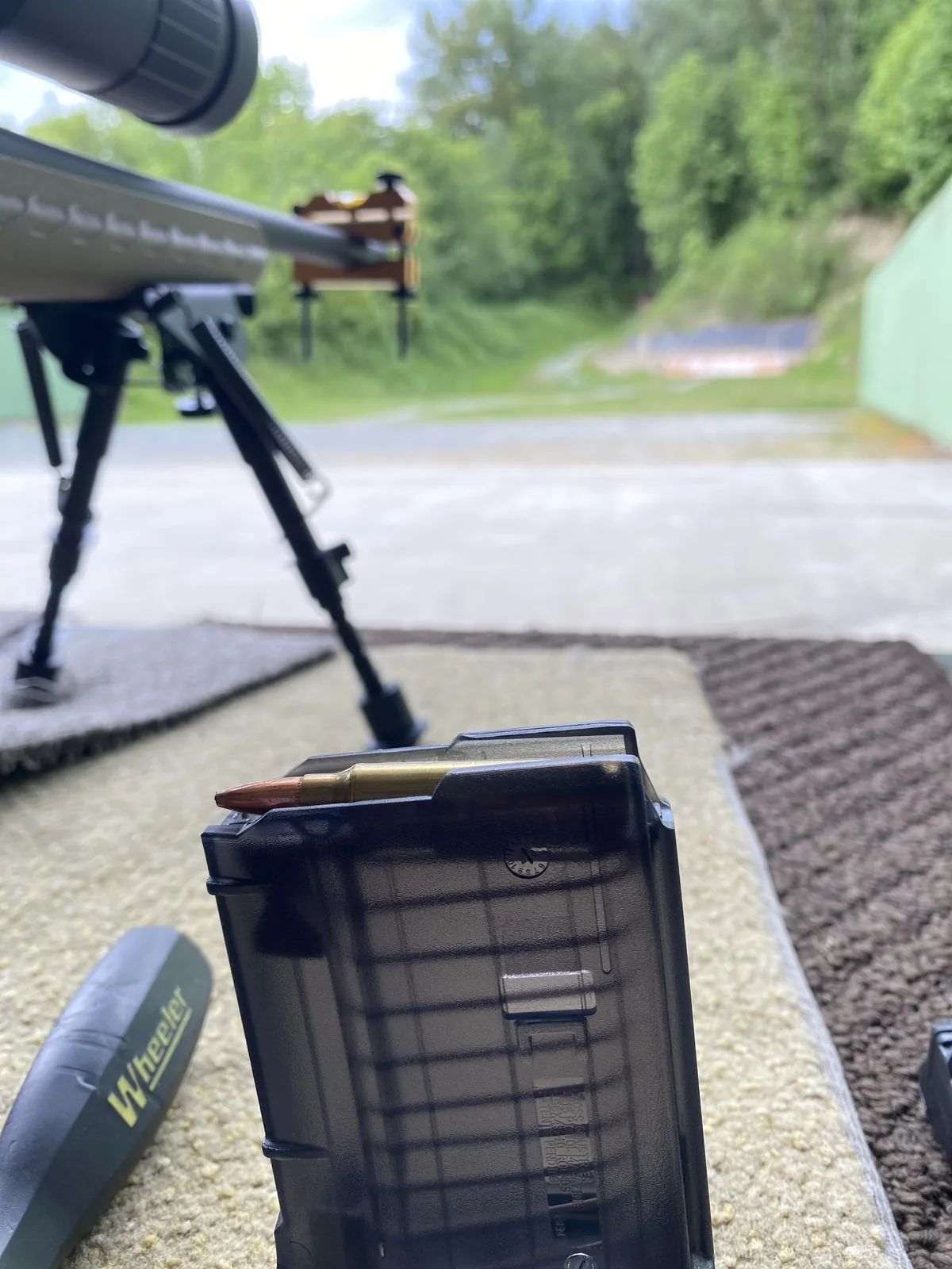 Loaded tinted polymer magazine with the Ruger American Ranch and deployed bipod behind it on the bench
