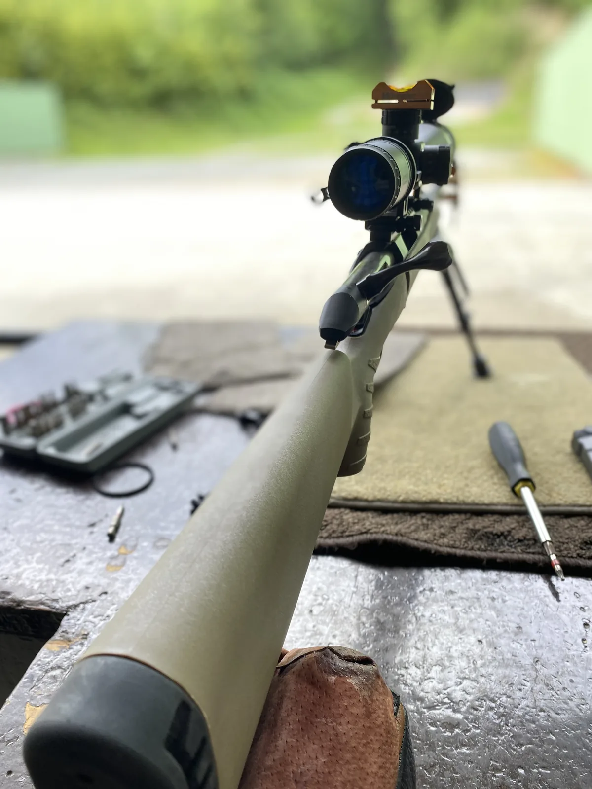 Down-the-stock view of the Ruger American Ranch from the buttpad, scope and bipod ahead, cleaning kit on the bench