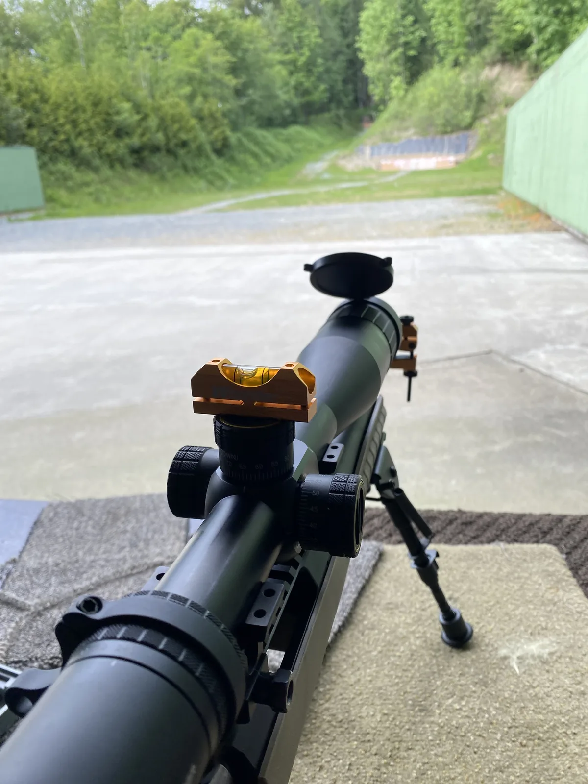 Down-the-barrel view of the Ruger American Ranch with a bubble level on the rail, range backdrop