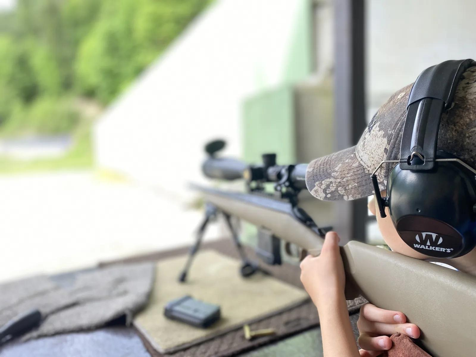 A young shooter behind the Ruger American Ranch on the bench, wearing Walker's ear protection