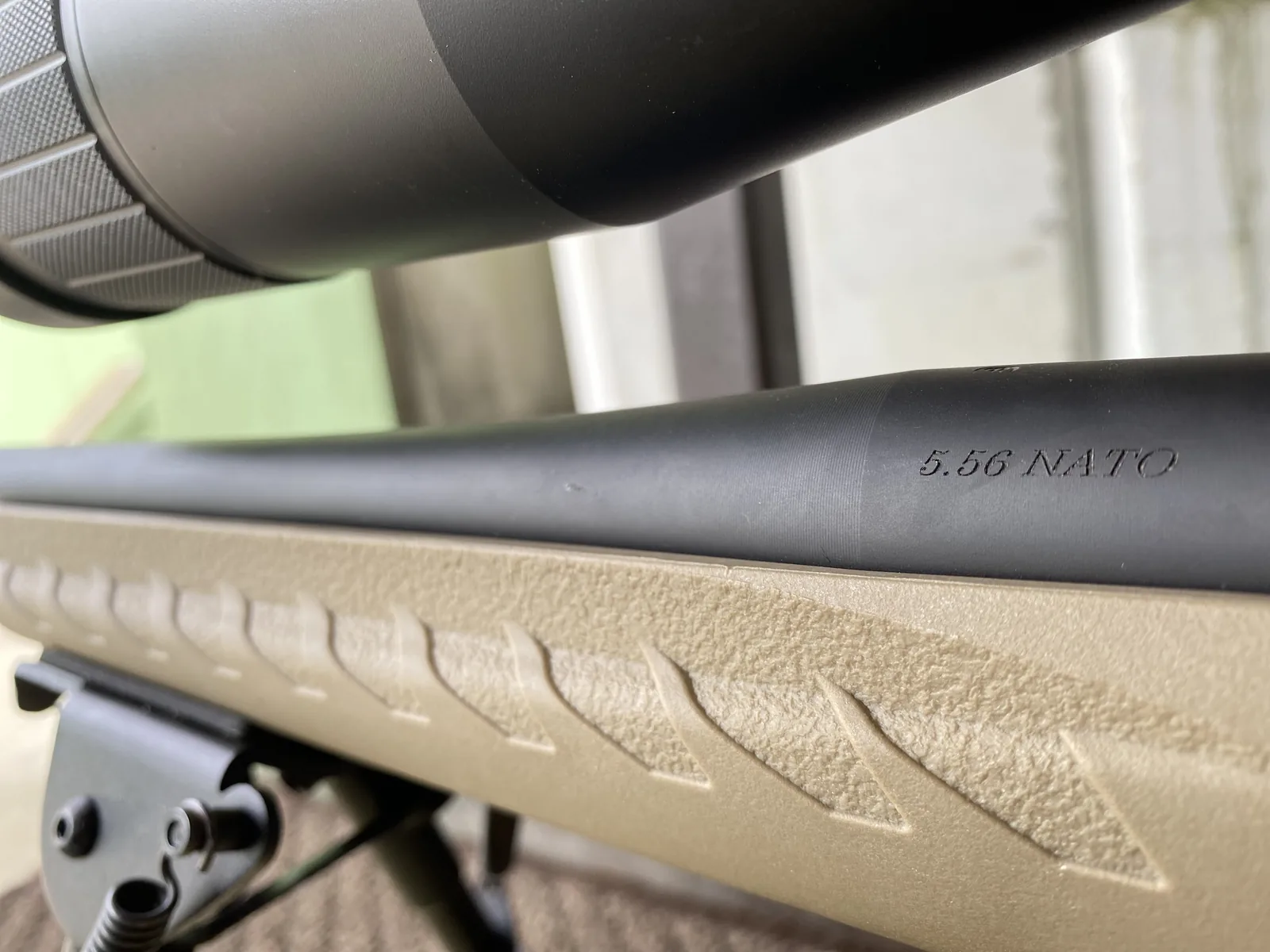 Close-up of the 5.56 NATO barrel stamp on the free-floated barrel above the textured FDE stock grip panel