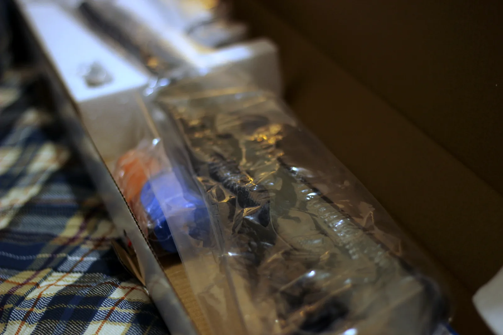 The rifle sealed in a plastic bag inside the open carton with the accessories alongside