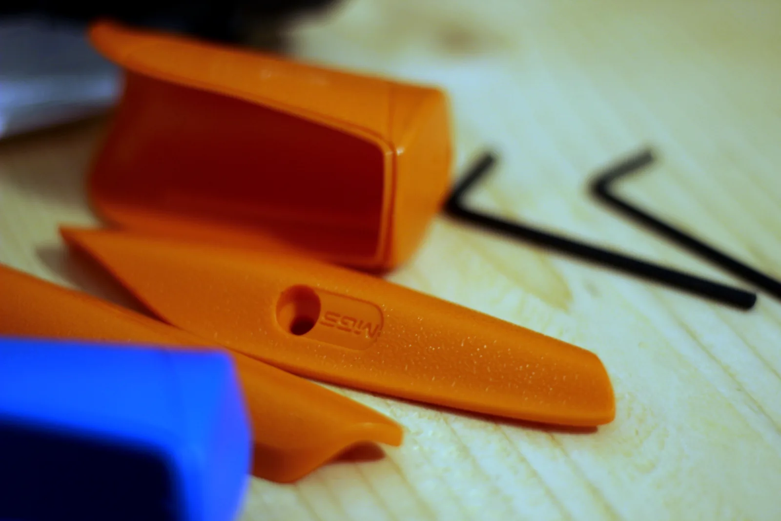 Orange and blue polymer Multi Grip System inserts and two hex keys on a wooden bench