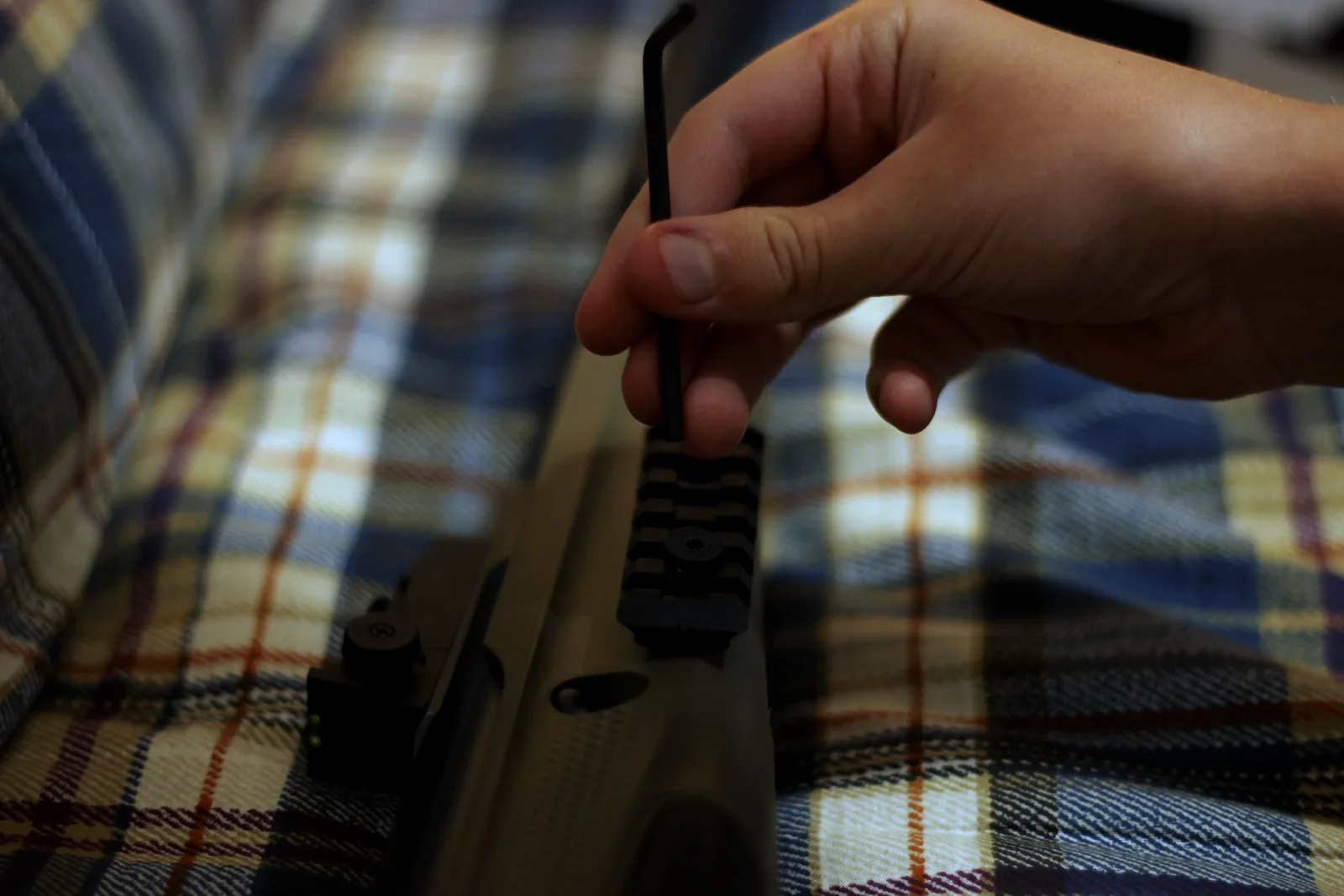 A hand fitting a polymer insert into the buttstock of the rifle with a hex key
