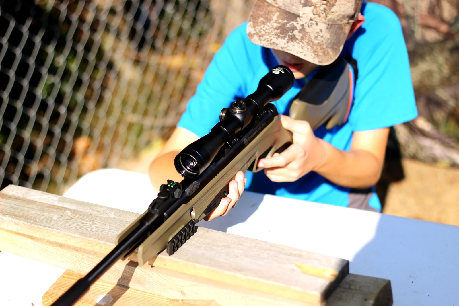 The young shooter taking a shot with the rifle supported on a wooden rest