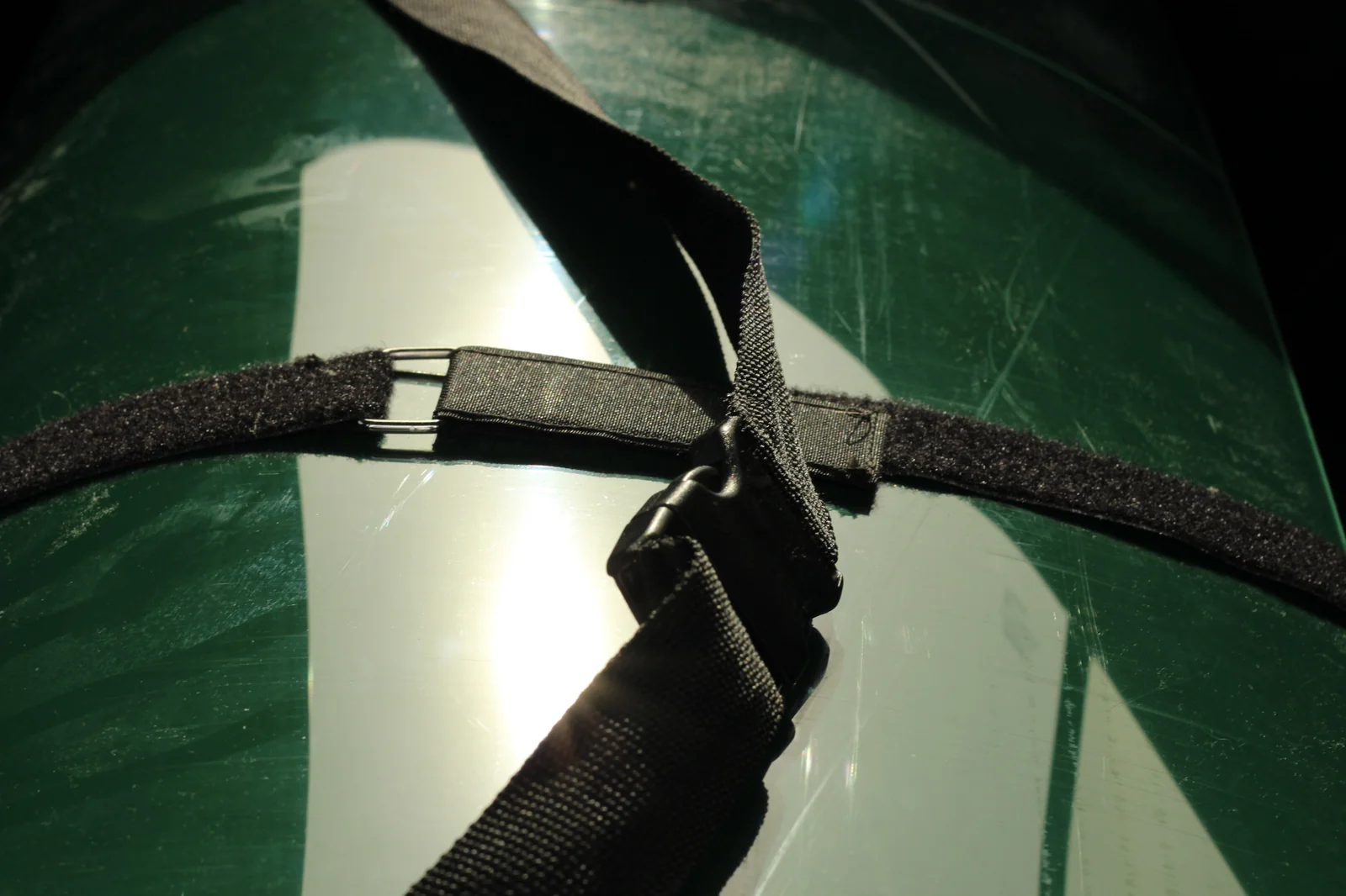 Close-up of the black webbing retaining strap with plastic side-release buckle and velcro keeper on the folded Tucktec hull