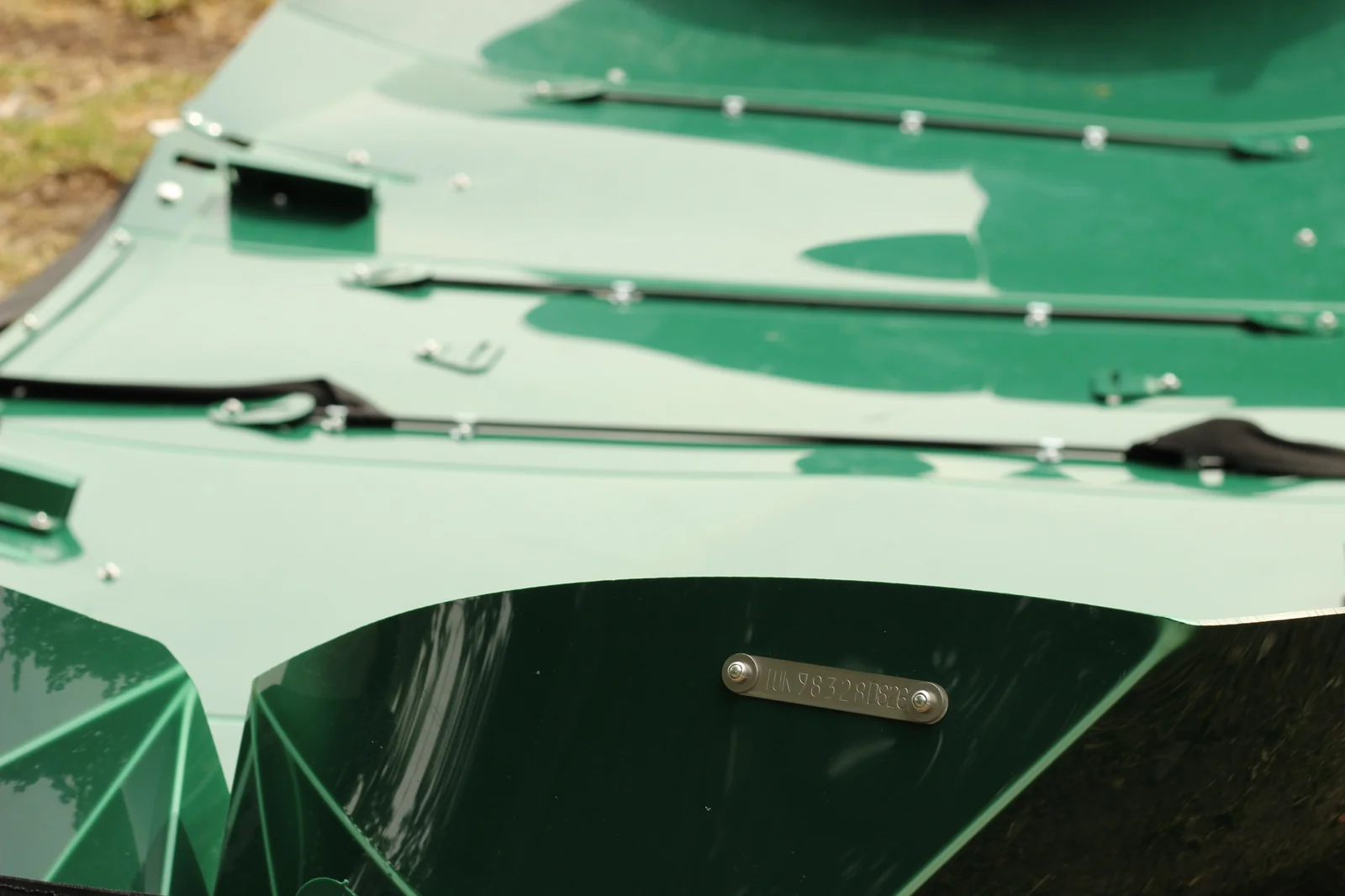 Close-up of the internal black metal frame rails riveted to the green hull panels with a small stamped metal serial number plate