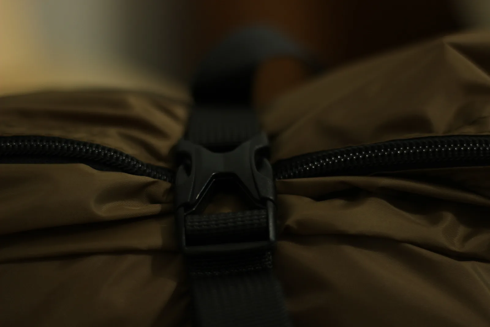 Close-up of a black side-release buckle joining two webbing straps across the brown stuff bag