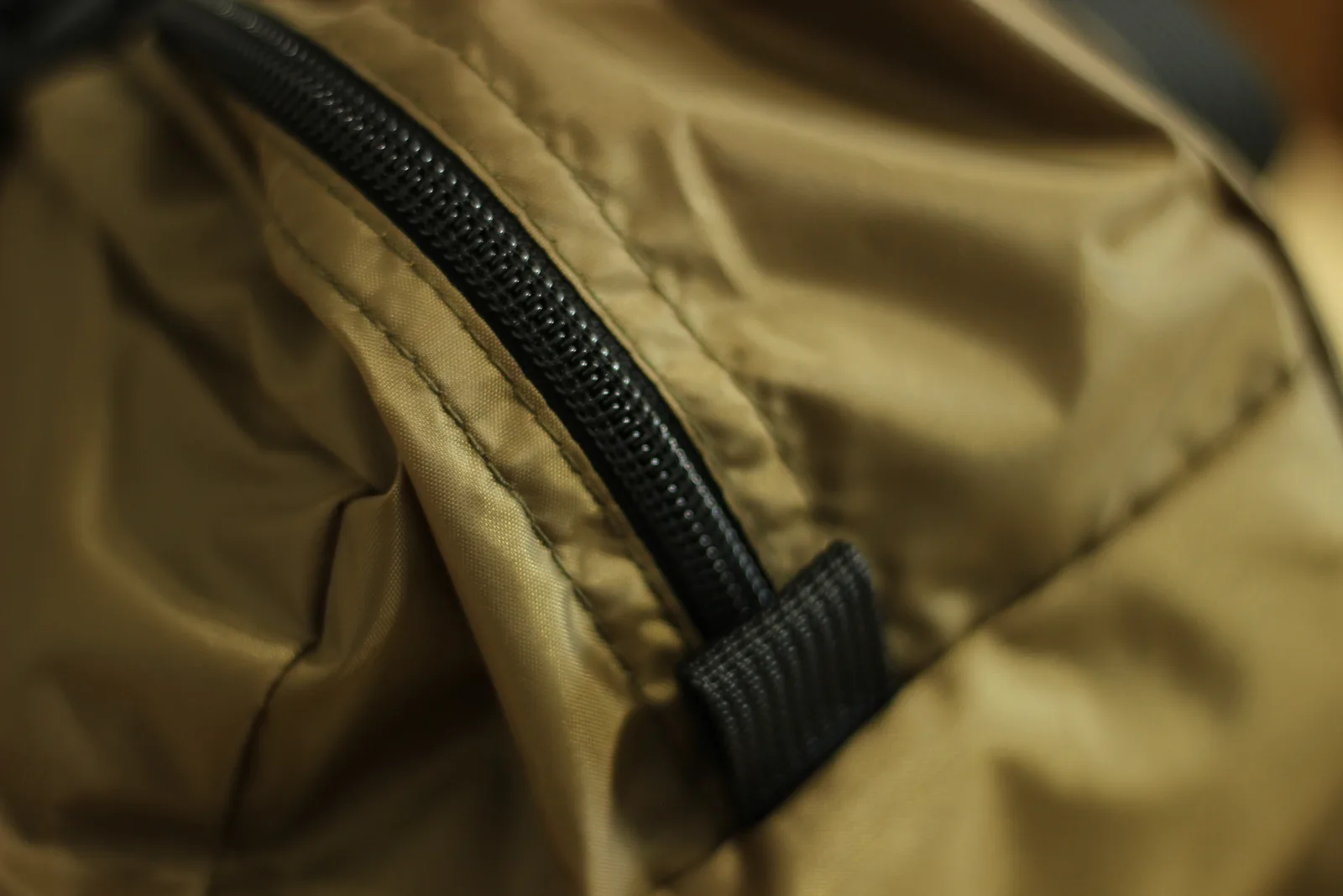 Macro of the bag's zip with a webbing pull tab and the double-stitched seam alongside