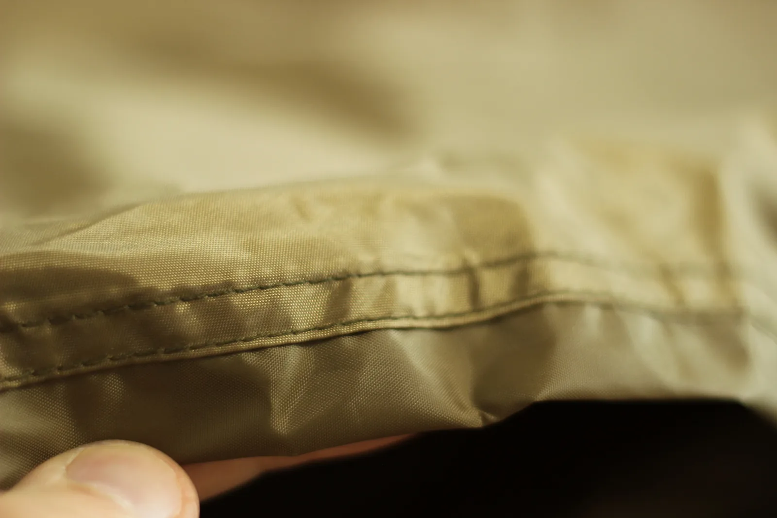 Close-up of the tent hem showing a rolled edge with two parallel rows of stitching