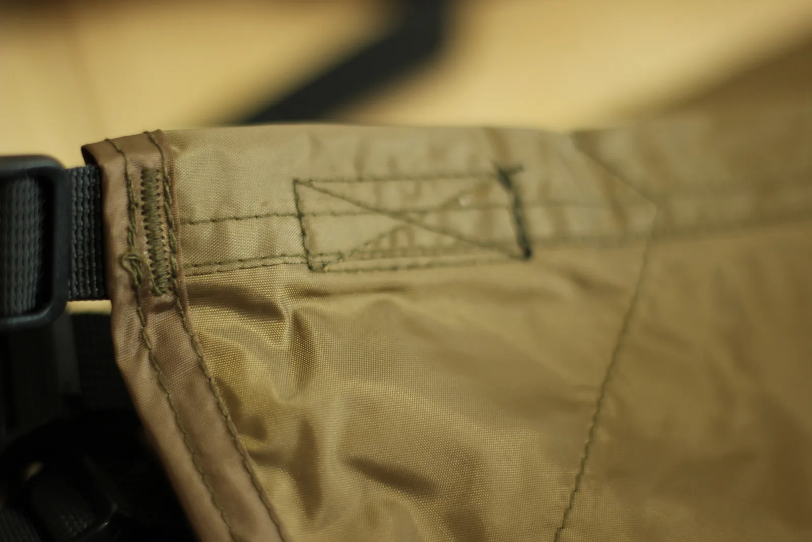 Close-up of a rectangular bar-tacked reinforcement patch stitched into the tent hem with a cross-hatch of stitching