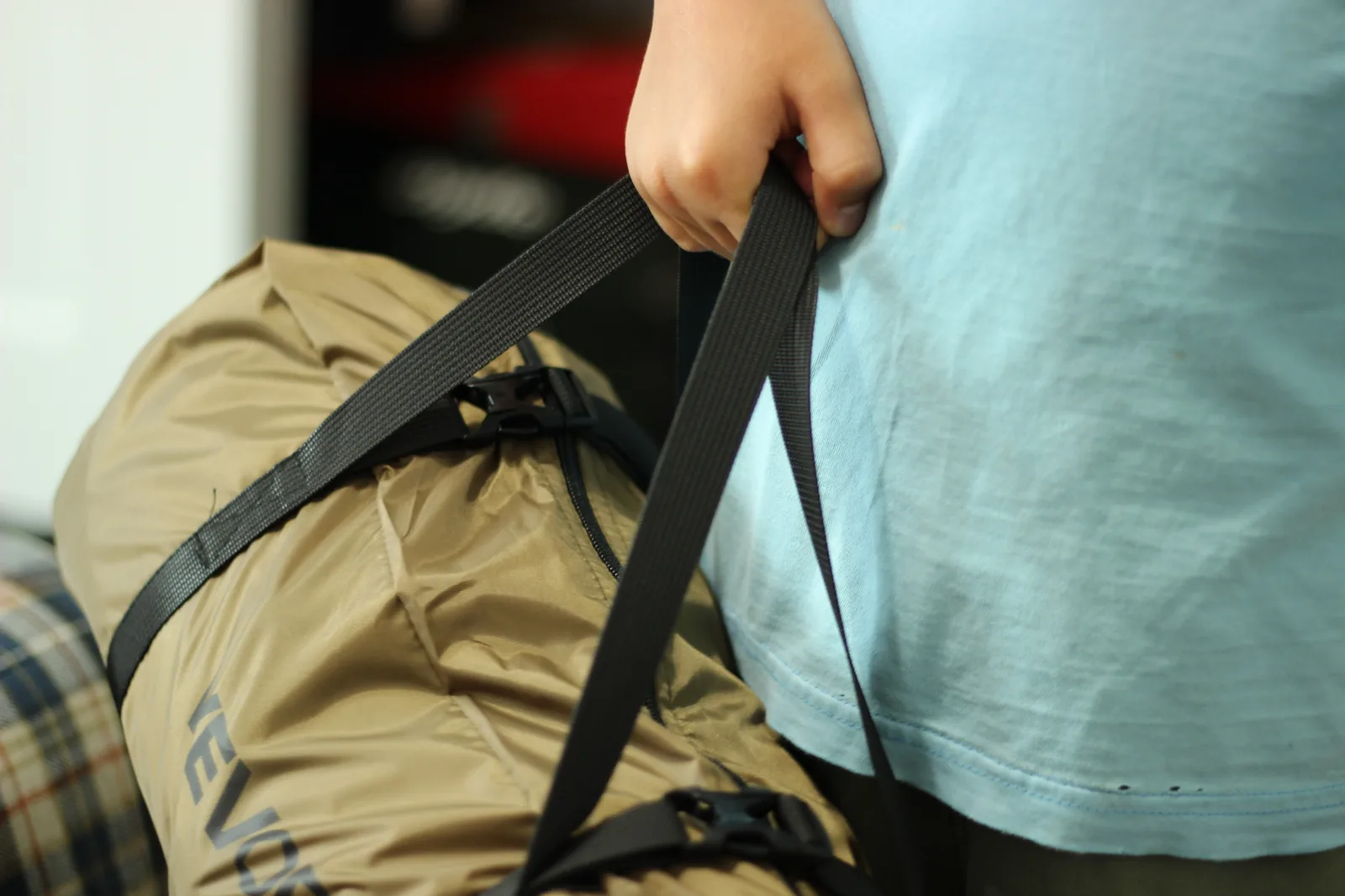 A person lifting the packed tent bag by its two webbing carry handles
