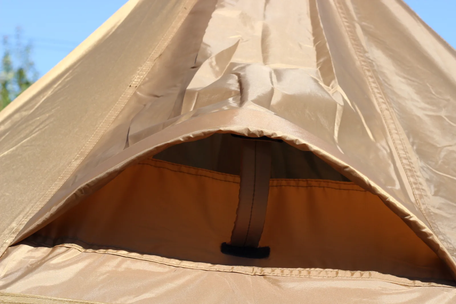 The vent opening near the peak of the pitched tent, a horizontal gap under a fabric hood with a webbing tab