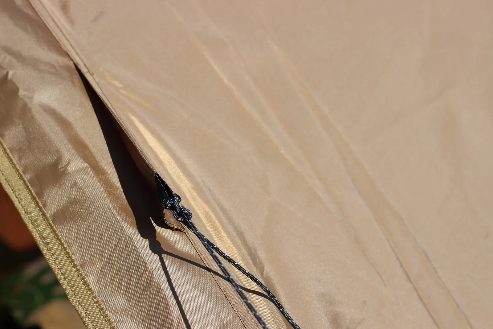 Close-up of the door zip running down the canopy with a black-and-white cord pull hanging from the slider