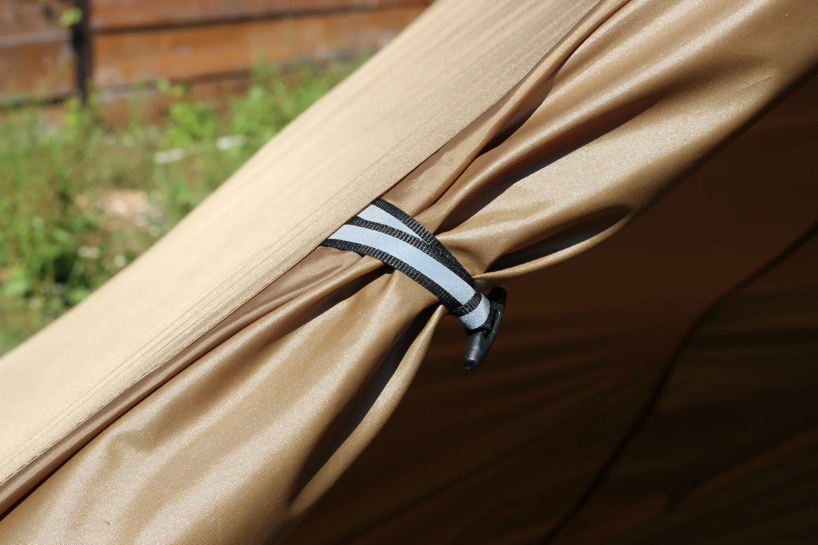 A reflective-striped webbing tab sewn to the canopy with a black plastic line adjuster hanging from it