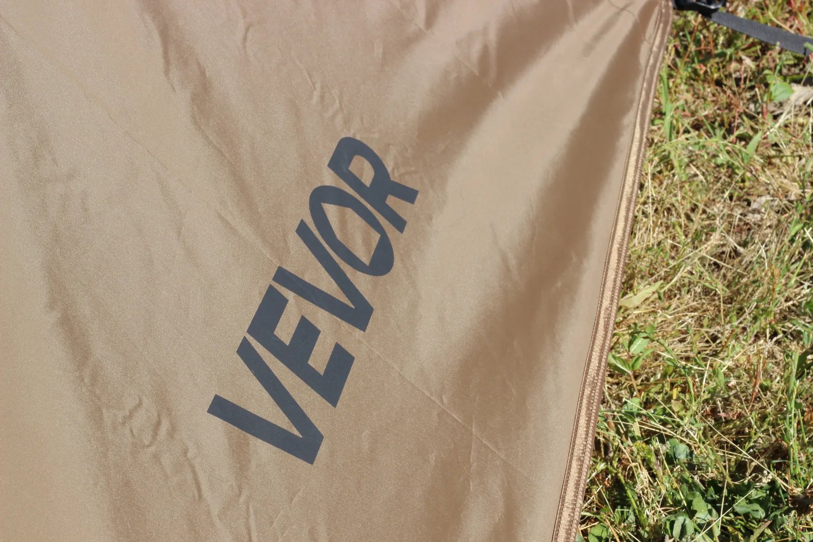 The VEVOR wordmark printed in dark grey on the coyote-brown canopy panel with grass alongside