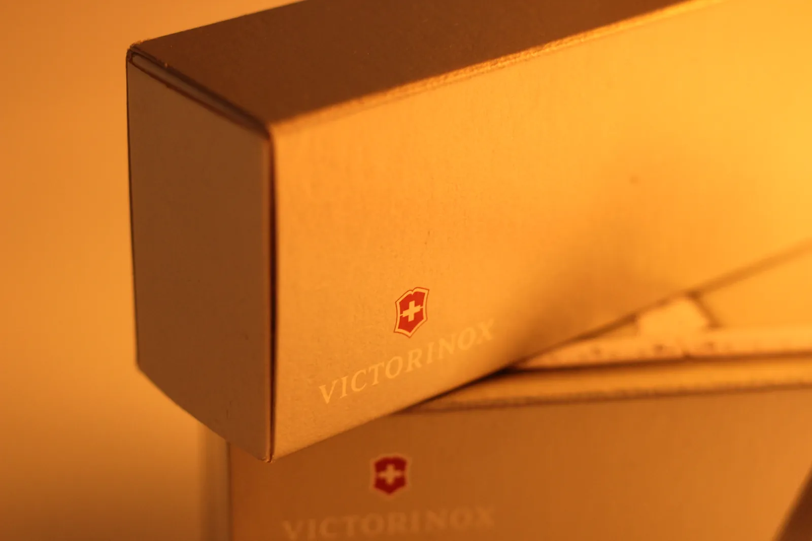 Close-up of the matte tan SwissChamp slipcase showing the Victorinox shield and wordmark catching warm light