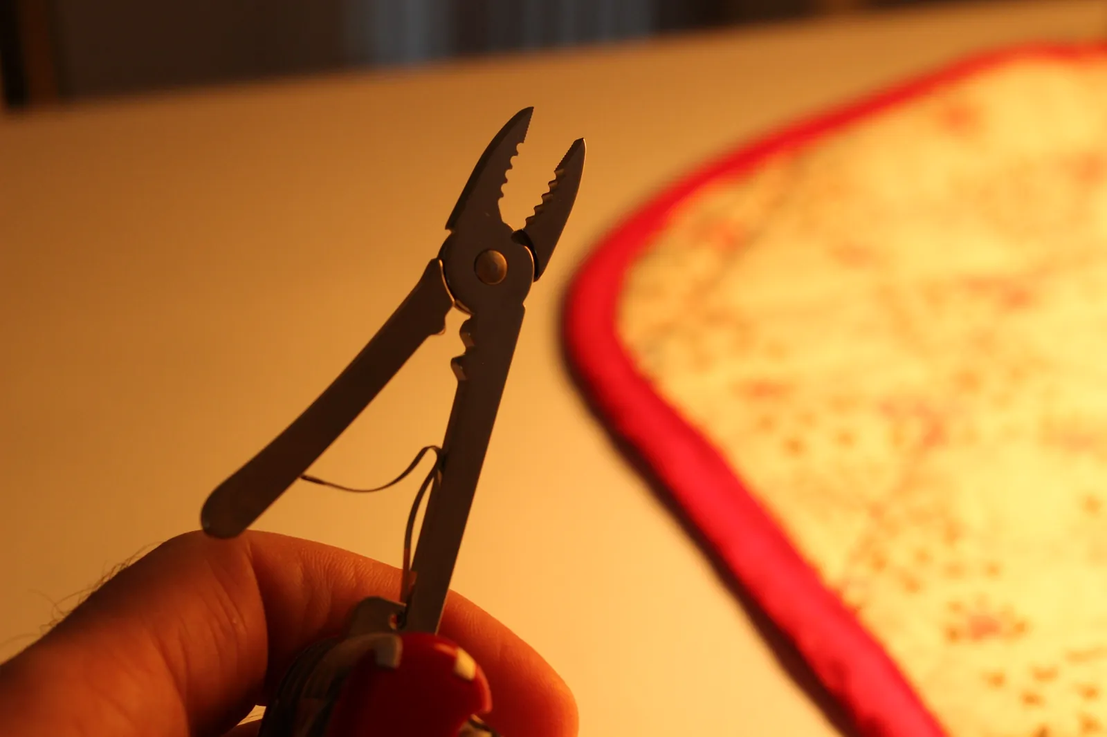 The SwissChamp pliers extended in hand from a different angle showing the toothed jaws and wire-cutter recess