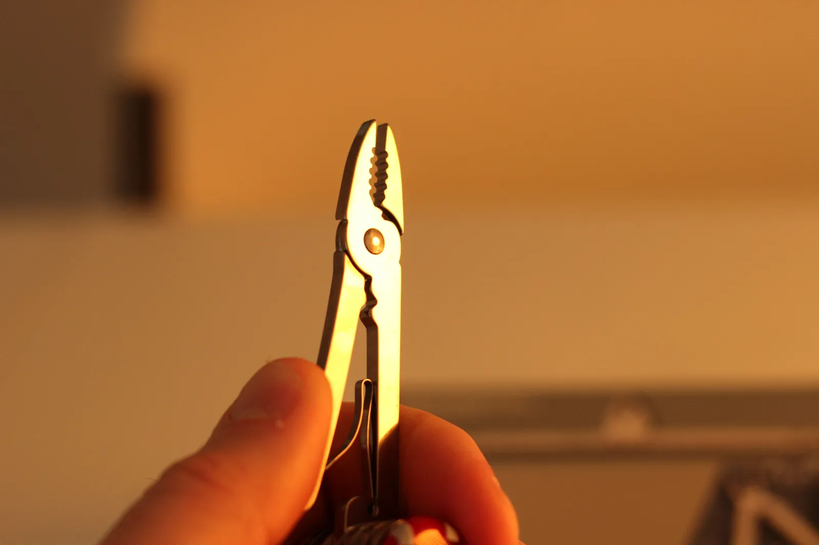 The SwissChamp pliers extended in hand showing the serrated jaws and the wire-crimper section in the handle