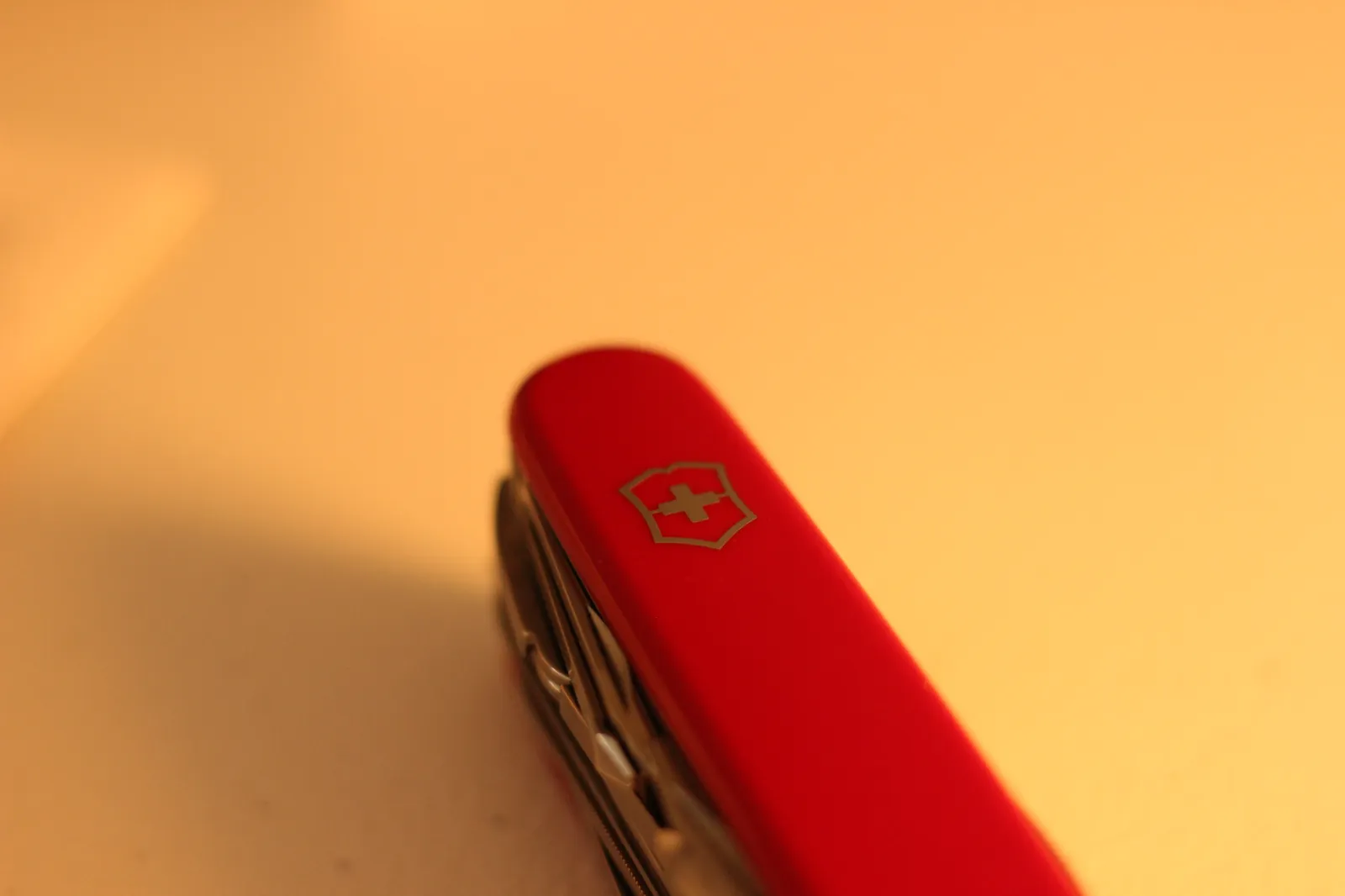 The closed SwissChamp on a sewing quilt with the Victorinox shield catching warm evening light