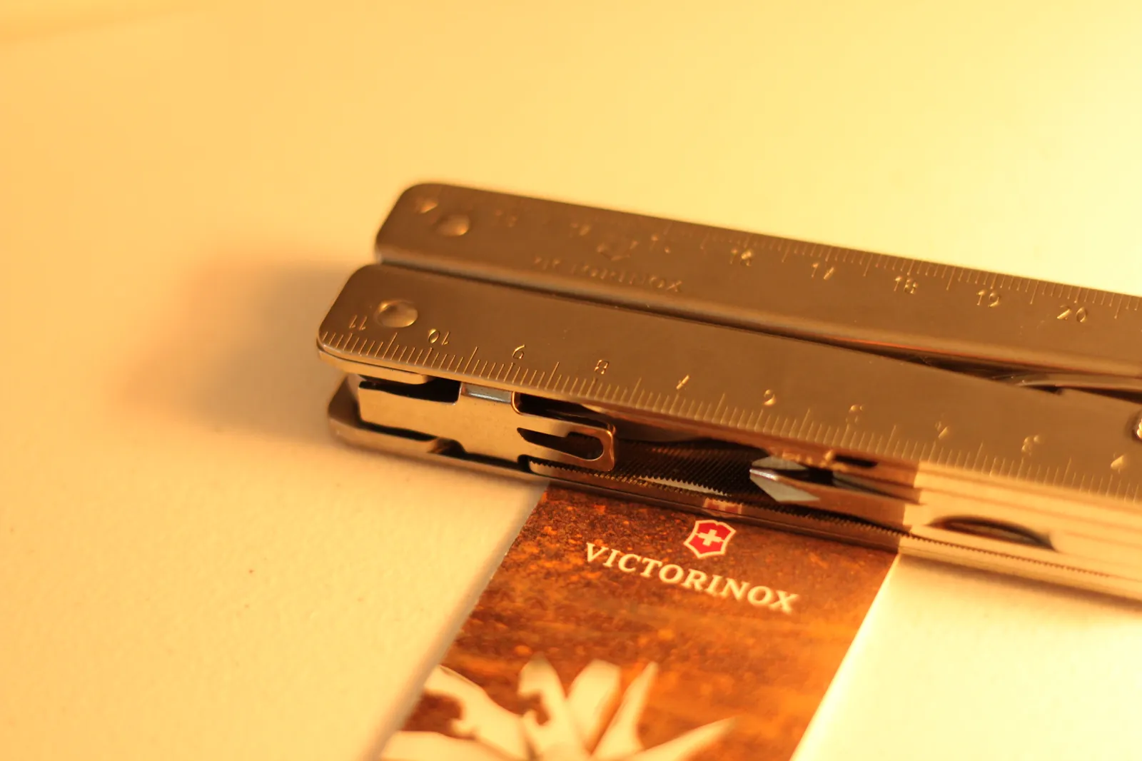 The Swiss Tool MX Clip closed in profile showing the integrated ruler edge with cm markings catching warm light