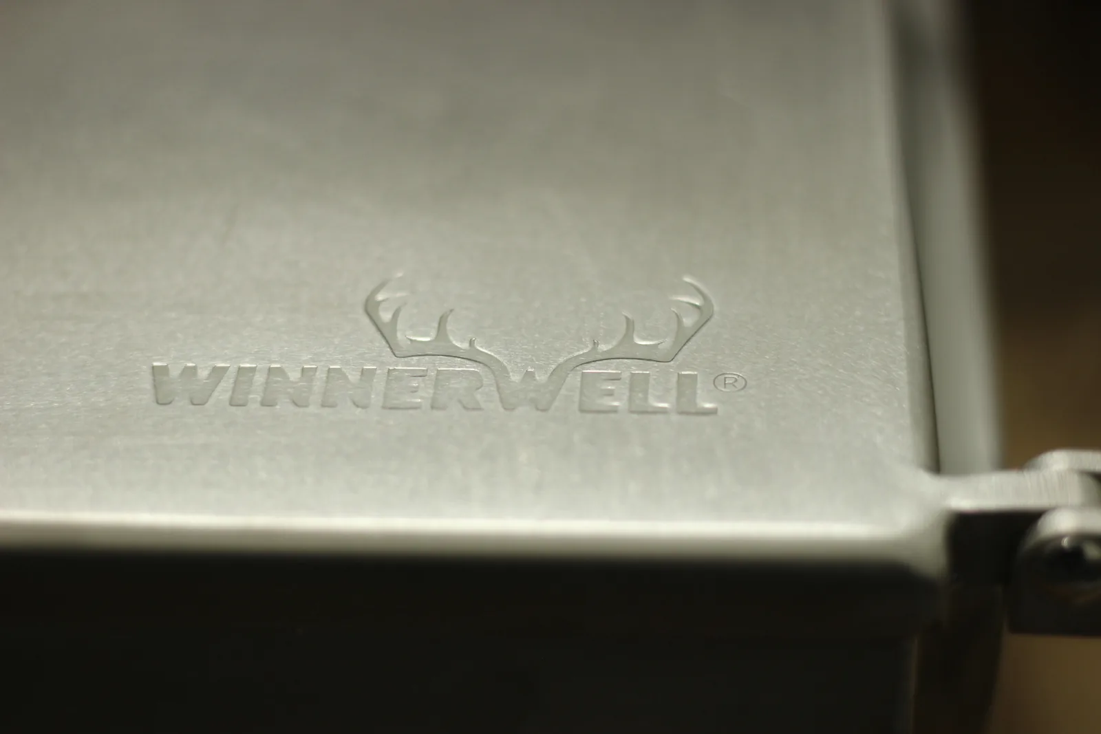 The Winnerwell antler logo embossed into the brushed stainless top plate of the stove