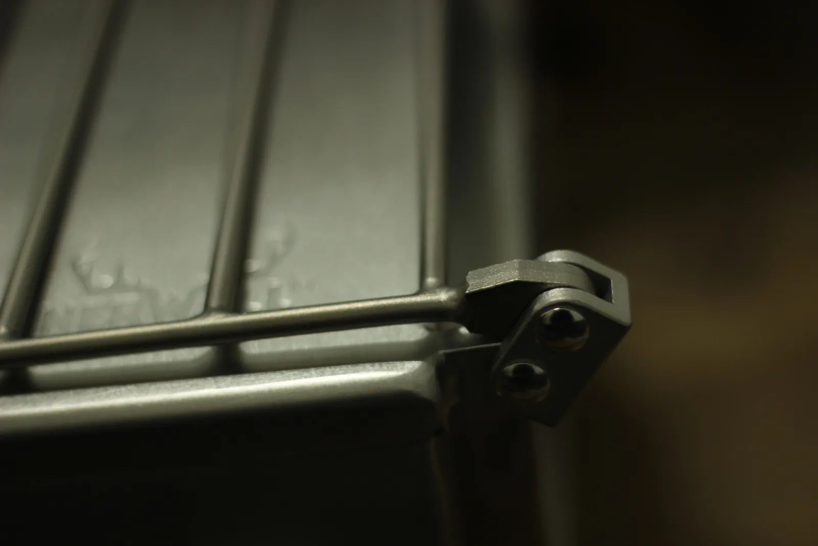 The same rack bracket photographed from the side showing the pivot and the two bolt heads
