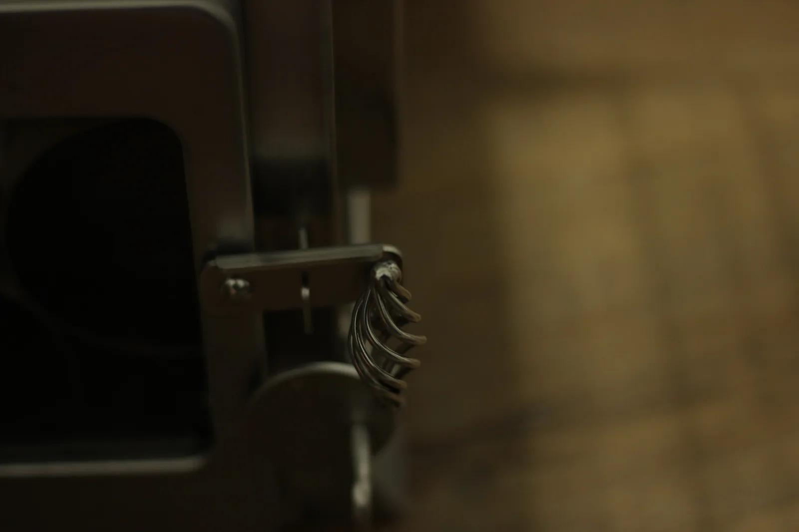 The coiled stainless spring handle on the stove door, photographed against a dark background