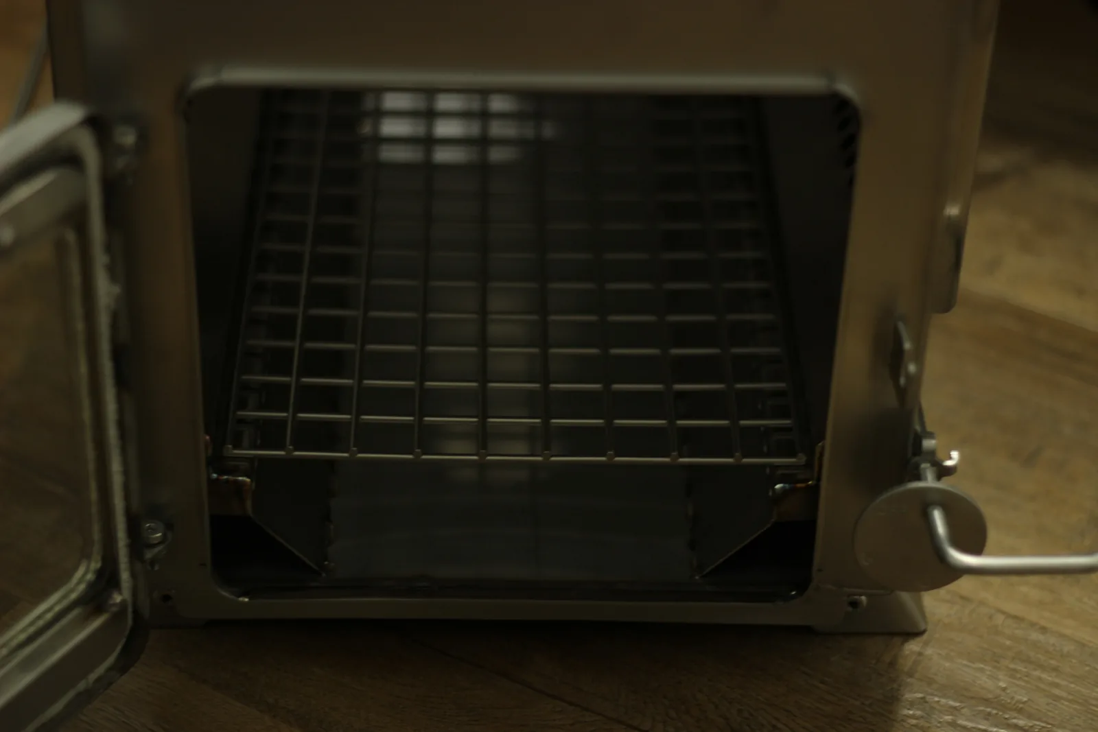 Looking into the empty firebox through the open door, showing the removable grate sitting above the floor