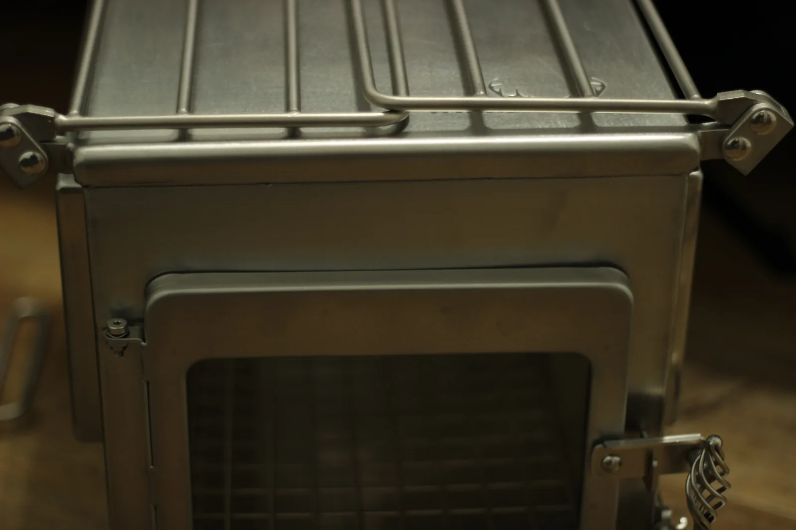 The stove with its front door swung open, the glass panel in the door and the wire rack folded above