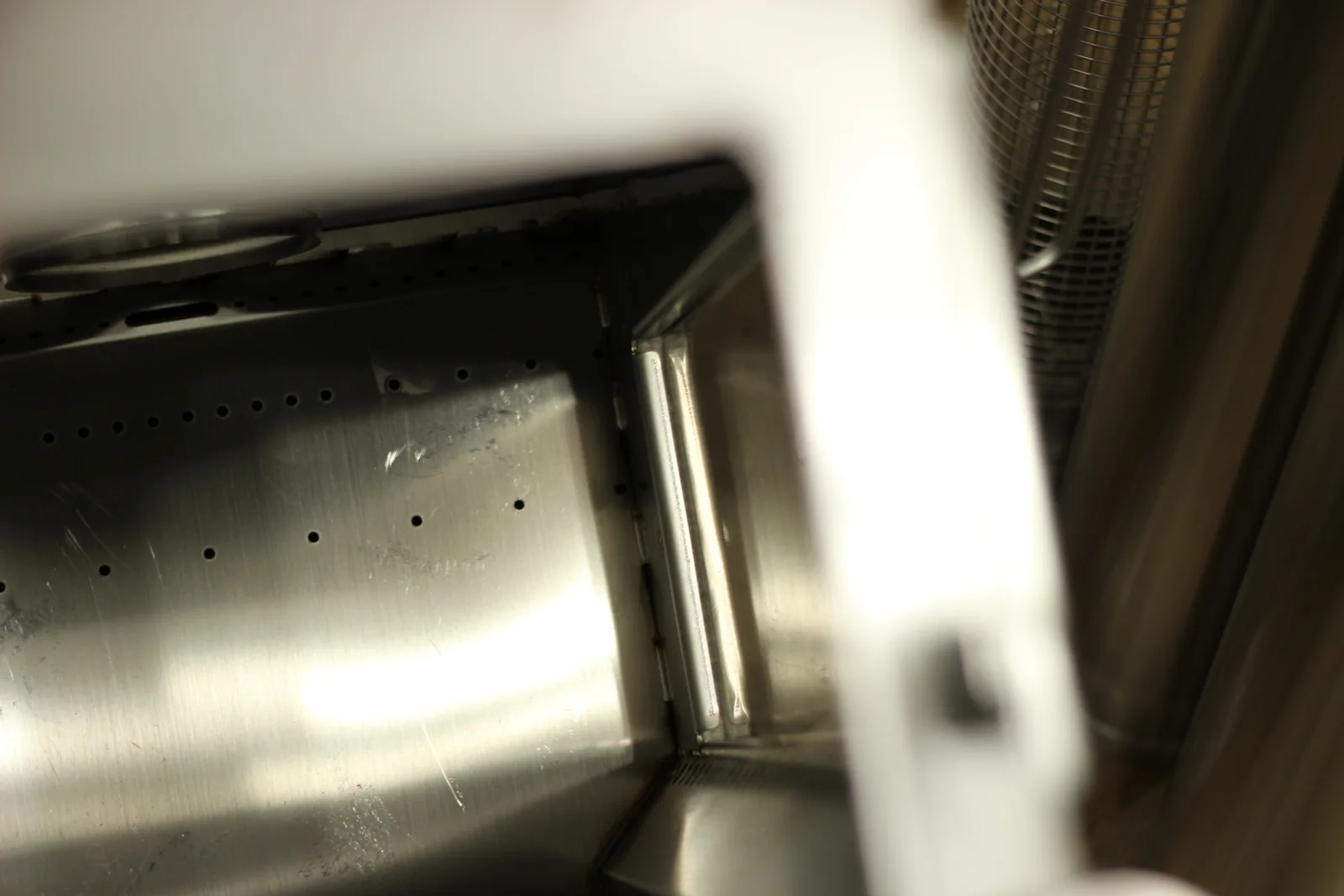 Inside the top of the firebox showing a row of small drilled holes along the upper wall for secondary combustion air