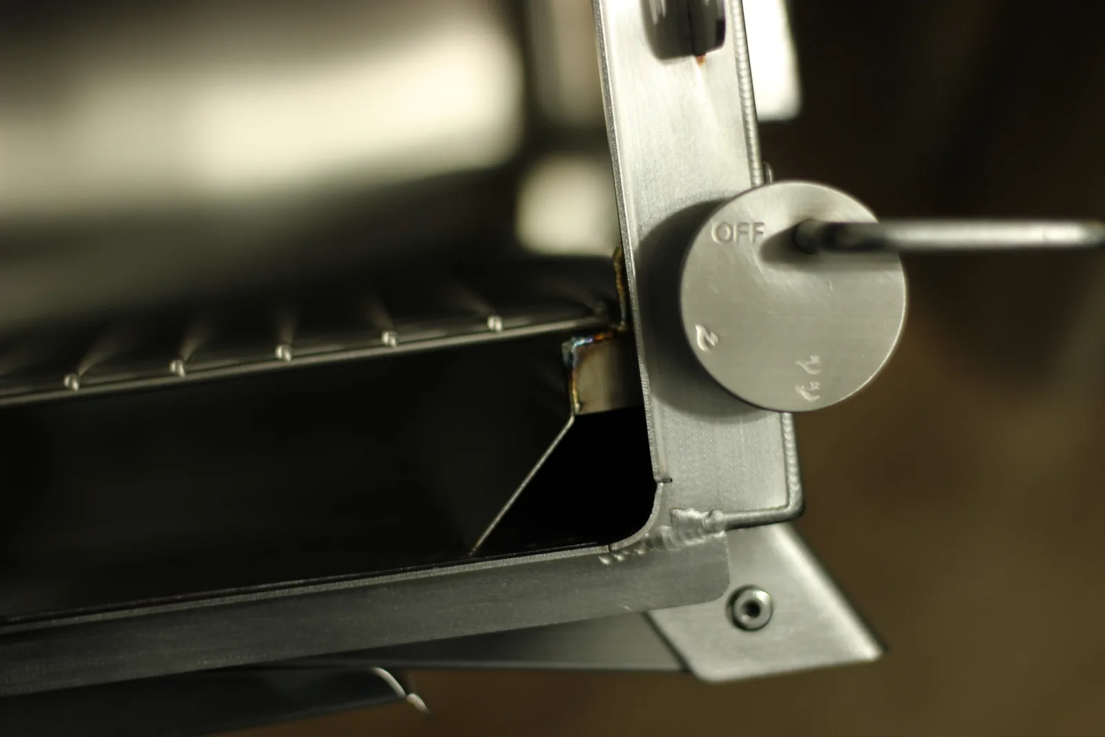 A round stainless air control dial on the stove marked OFF at one end of its travel