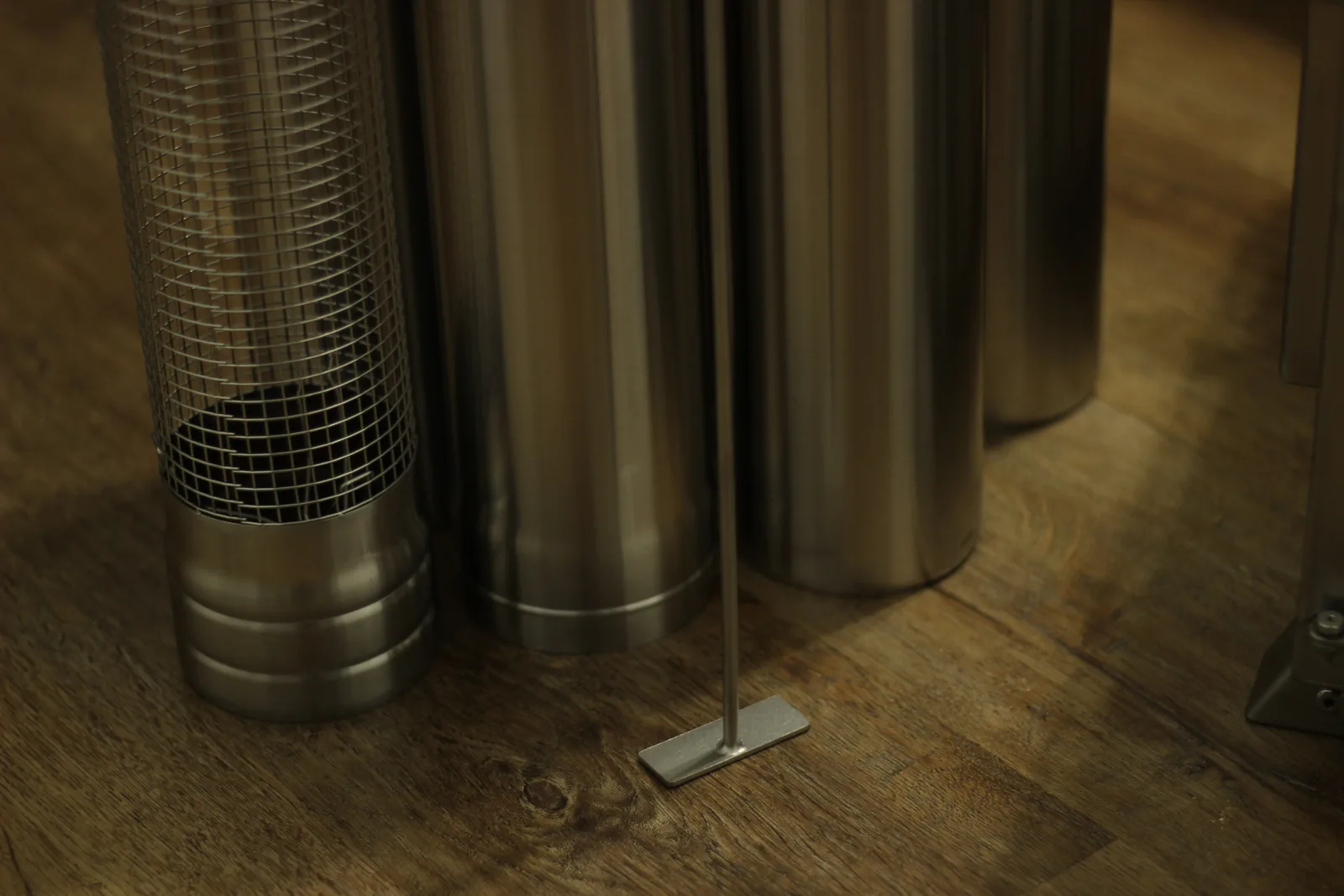 The perforated mesh spark arrestor standing beside the smooth stainless chimney sections on a wooden floor