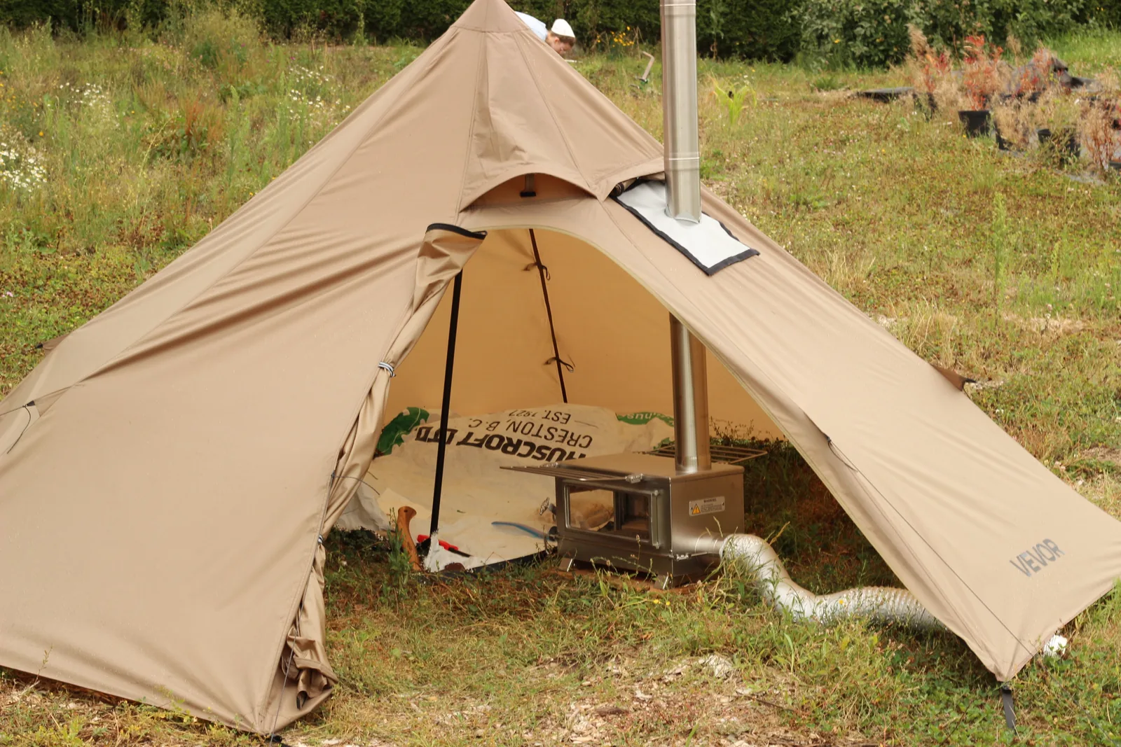 The pitched tent from outside with the chimney rising from the stove jack panel on the canopy