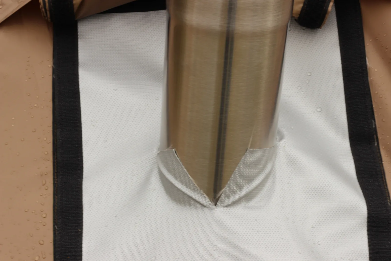 The stainless chimney rising through the pale flame-retardant stove jack panel in the tent canopy