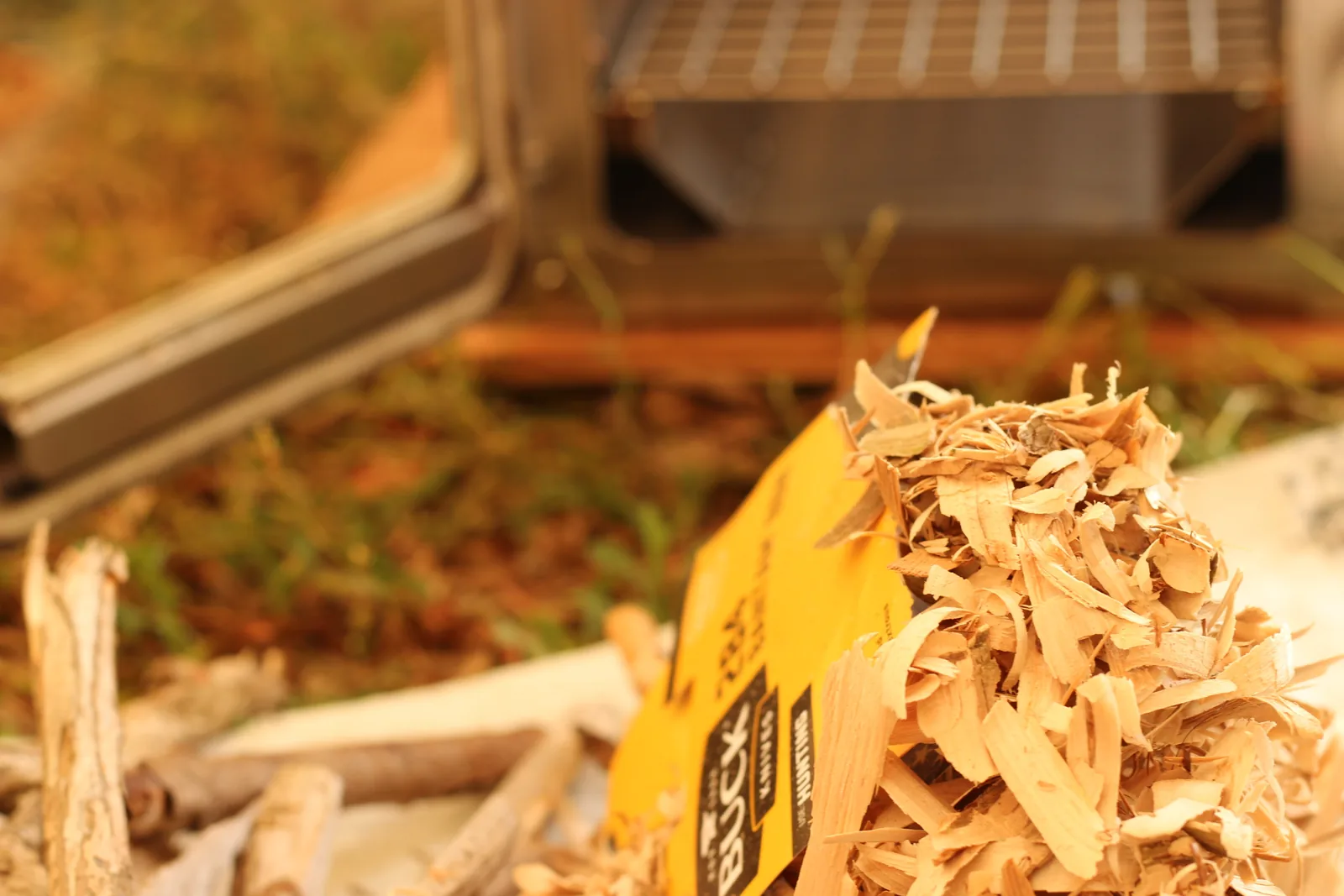 A heap of pale wood shavings and split kindling on a tarp beside the open stove door